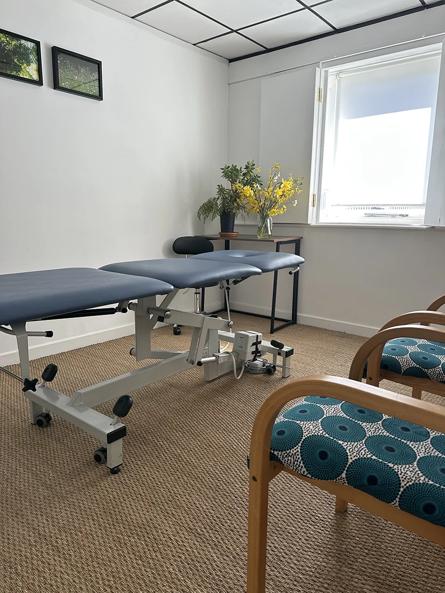 Therapy room at Hereford Yoga Centre showing treatment couch, seating area and natural light from the window.